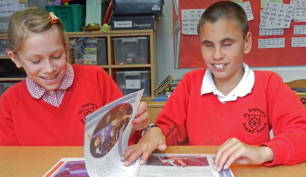 a braille-reading student and a sighted student sharing a book in the classroom