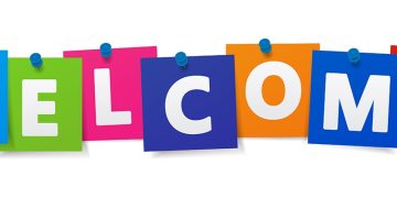 The word 'welcome' is made up of each letter on a brightly-coloured card, hanging on a washing line held with blue pegs.